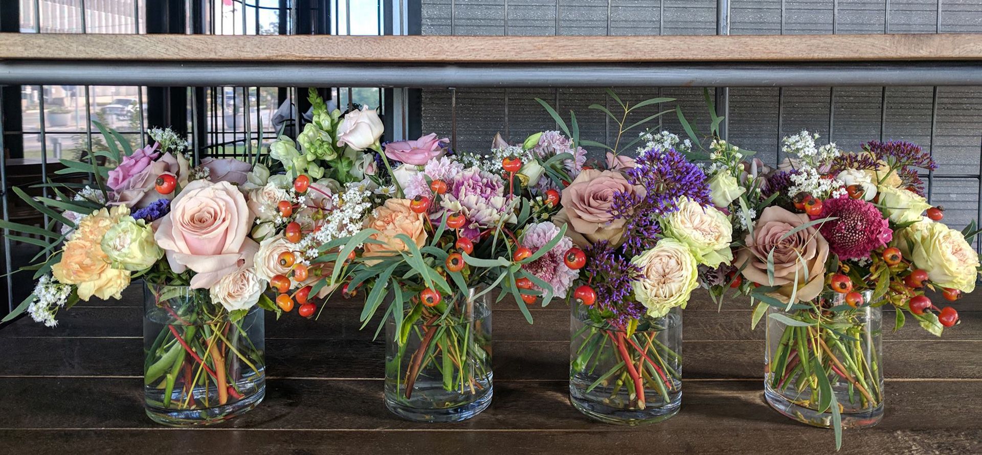 flowers in vases lined up in restaurant before being placed on tables
